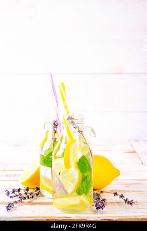 Eiskalte Lavendellimonade, Zitrone, Stroh. Zwei klassische Mojito-Drinks, alkoholfreier Cocktail mit Eis in zwei Vintage-Hipster-Flaschen, auf grunged Stockfoto