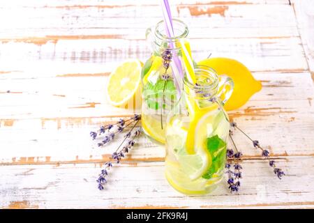 Eiskalte Lavendellimonade, Zitrone, Stroh. Zwei klassische Mojito-Drinks, alkoholfreier Cocktail mit Eis in zwei Vintage-Hipster-Flaschen, auf grunged Stockfoto