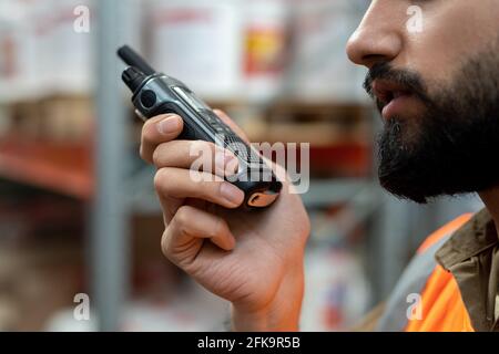Nahaufnahme eines ernsthaften bärtigen Vertriebsleiters mit Walkie-Talkie während der Arbeit Im Lager Stockfoto