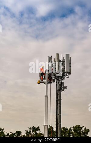 Pencoed, in der Nähe von Bridgend, Wales - April 2021: Ingenieur in einer hydraulischen Plattform an der Spitze eines Mobilfunkmastes für Wartungsarbeiten Stockfoto