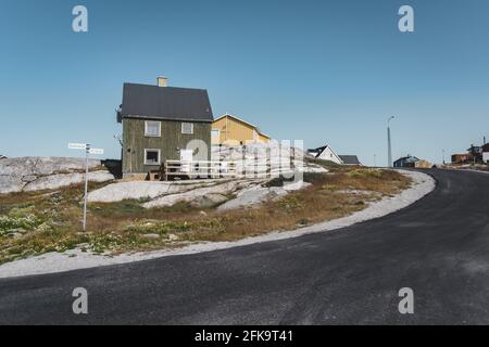 Typisches hölzernes buntes Fischerhaus mit Eisberg in der Disko Bay Area Grönland und Ilulissat. Typische Architektur im arktischen Kreis. Sommer und Stockfoto