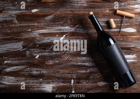 Vintage Flasche Rotwein mit leerem mattschwarzes Etikett, Korkenzieher auf grunged Holztisch Hintergrund. Teure Flasche cabernet-sauvintekonzept. Stockfoto