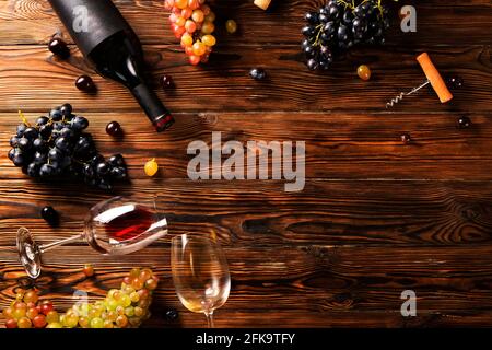 Vintage Flasche Rotwein mit leerem mattschwarzes Etikett, Korkenzieher & Trauben Trauben auf Holztisch Hintergrund. Teure Flasche cabernet-sauviny Stockfoto