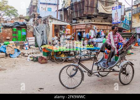 VARANASI, INDIEN - 25. OKTOBER 2016: Straßenobststände und eine Rikscha-Rikscha in Varanasi, Indien Stockfoto