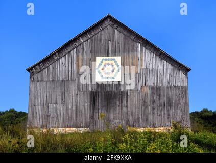 Die alte, verwitterte Scheune ist Teil eines Quiltweges in Tennessee. Der Himmel ist lebhaft blau und umgibt eine Scheune. Stockfoto