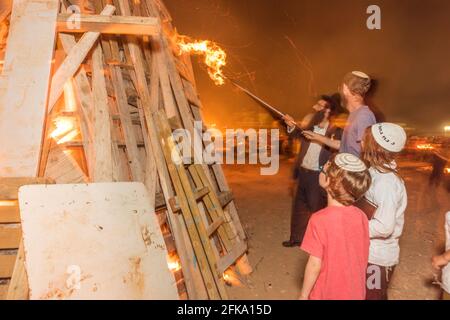 Ein Rabbi zündet einen großen Scheiterhaufen während des jüdischen Feiertages von lag Ba'Omer an, der jeden 18. Des hebräischen Monats Iyar stattfindet. An diesem Feiertag ist es üblich, Brände zu machen. In diesem Jahr wurden alle Brände aufgrund einer Brandgefahrenwarnung auf wenige Standorte konzentriert, was auf die große Anzahl von Scheiterhaufen zurückzuführen ist. Stockfoto