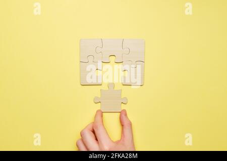 Person montiert ein Holzpuzzle und verbindet das letzte Stück. Stockfoto