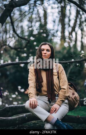 Schönes Mädchen im Park sitzt auf einem Baum Stockfoto