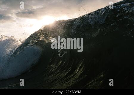 Wellenbrechung bei Sonnenuntergang am Strand Stockfoto