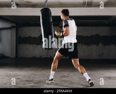Junge Muskel Boxer mit einem Boxsack in der Turnhalle. Boxer schlagen Stanzgeschwindigkeit Tasche Stockfoto