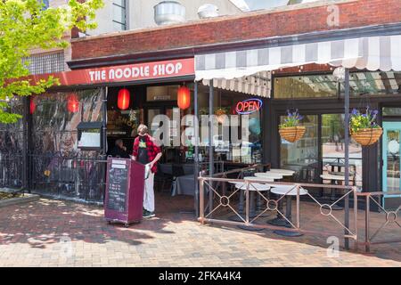 ASHEVILLE, NC, USA-25 APRIL 2021: Der Covid-maskierte Oberkellner oder Maitre d' im Noodle Shop bereitet sich auf ein geschäftiges Mittagessen an einem Außenstand vor. Stockfoto