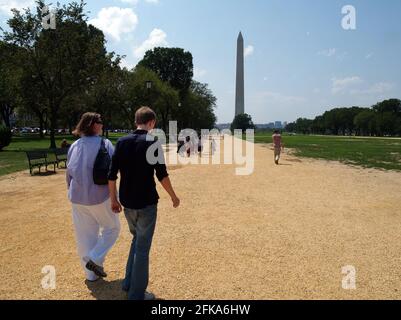 Im Sommer laufen eine Frau und ein junger Mann oder Teenager-Sohn die National Mall entlang zum Washington Monument. Stockfoto