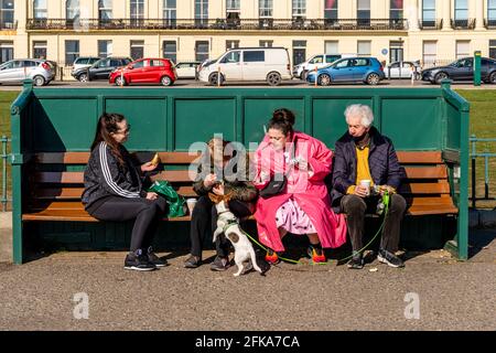 Eine Gruppe von Einheimischen, die die Sonne auf der Hove Seafront genießen, Brighton, East Sussex, Großbritannien. Stockfoto