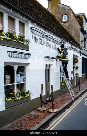 Eine Schilderin, die an EINEM Pub Exterior, Rottingdean, East Sussex, Großbritannien, arbeitet. Stockfoto