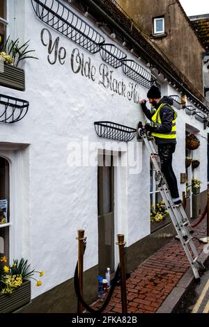 Eine Schilderin, die an EINEM Pub Exterior, Rottingdean, East Sussex, Großbritannien, arbeitet. Stockfoto