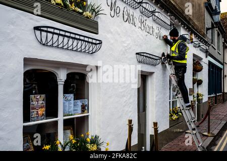 Eine Schilderin, die an EINEM Pub Exterior, Rottingdean, East Sussex, Großbritannien, arbeitet. Stockfoto