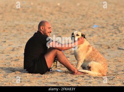 Beirut, Libanon. April 2021. Ein Mann genießt sich mit seinem Hund an einem Strand in Beirut, Libanon, 28. April 2021. Die libanesische Katastrophenrisikomanagement-Einheit kündigte an, dass im Libanon vom 1. Bis 4. Mai eine Sperre verhängt werden soll, um die Sozialisierungs-Aktivitäten während der orthodoxen Osterzeit zu beschränken. Quelle: Liu Zongya/Xinhua/Alamy Live News Stockfoto