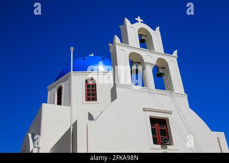 Weiße Kirchenglocken und blaue Kuppel vor blauem Himmel in Oia, Santorini Stockfoto
