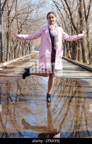 Mädchen tanzt auf einer Pfütze mit Bäumen Reflexion Stockfoto