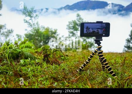 Smartphone mit Mini-Stativ in wunderschöner Landschaft. Fotos von mobilen Stativbildern. Stockfoto