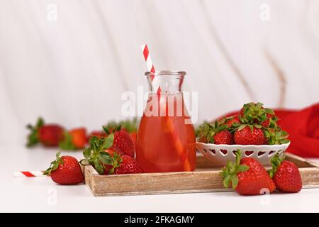 Rote Erdbeerfrucht Limonade im Glas, umgeben von Beeren Stockfoto