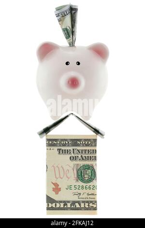 Amerikanische 100-Dollar-Währung in rosa Sparschwein, das auf dem Haus steht, aus US-Geld, das auf Weiß isoliert ist, und das ideal die Ersparnisse, Kredite, real darstellt Stockfoto
