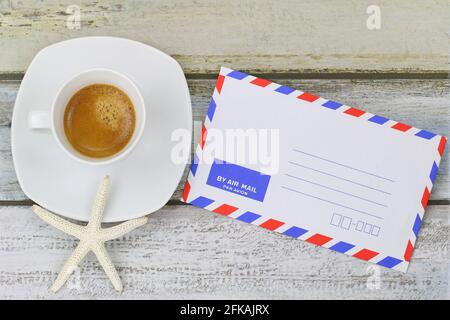 Seestern auf frisch gebrühtem Espresso-Kaffee neben leerem Klassiker Umschlag für Luftpost Stockfoto