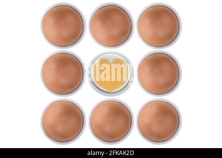 Eierbecher voll mit frischen Hühnereiern aus freier Wildpalette, ein Querschnitt zeigt gekochtes herzförmiges Eigelb und Eiweiß, isoliert auf weißem Hintergrund Stockfoto