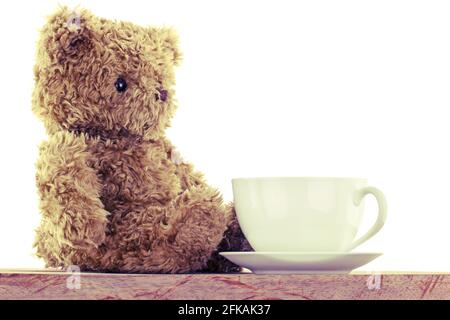 Seitenprofil eines niedlichen Bären, der neben Weiß sitzt Heißer Kaffeebecher auf Holzboden mit Vintage-Filter Stockfoto