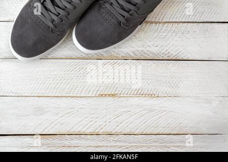 Ein paar neue stylische Skateboard Schuhe für Herren Graue Farbe auf weißem Holzhintergrund Stockfoto