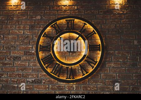 Schwarze leuchtende Uhr auf Backstein Hintergrund Stockfoto