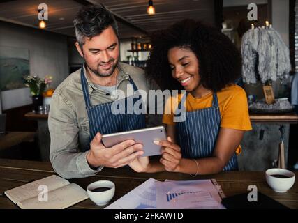 Kollegen lächeln mit Lernmenü des Ladens stehen mit heiß Kaffee im trendigen Café Stockfoto