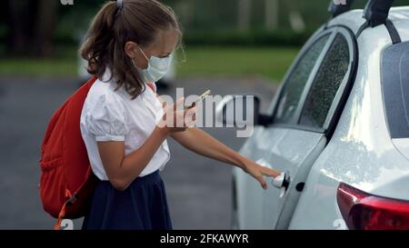 Nette Schüler mit Smartphones an der Grundschule. Junge und Mädchen in Sicherheitsmasken mit Gadgets in den Händen. Stockfoto