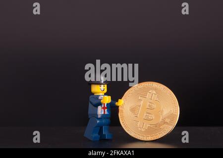 LEGO Geschäftsmann hält Kryptowährung Bitcoin BTC physische Goldmünze, Crypto-Handel Stockfoto