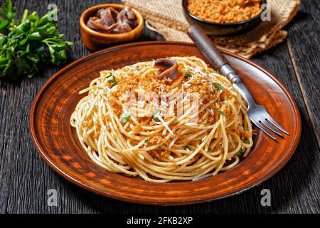 Pasta mollicata: Spaghetti mit Sardellen und gerösteten Paniermehl, Parmesankäse und Petersilie - traditionelles süditalienisches Gericht, serviert auf einem Teller o Stockfoto