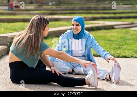 Muslimische Mädchen mit Hijab Stretching mit ihrem Freund im Park nach dem Training. Stockfoto
