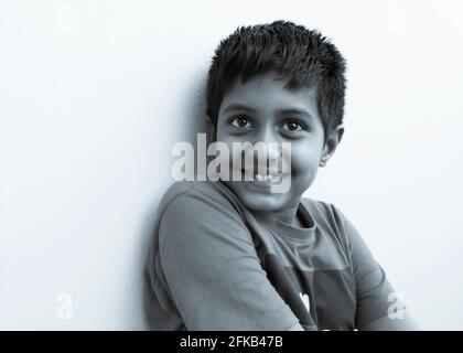 Nahaufnahme eines indischen Jungen, der isoliert auf weißer Oberfläche in Schwarz-Weiß lächelt, Kalaburagi, Karnataka, Indien-April 27.2021 Stockfoto