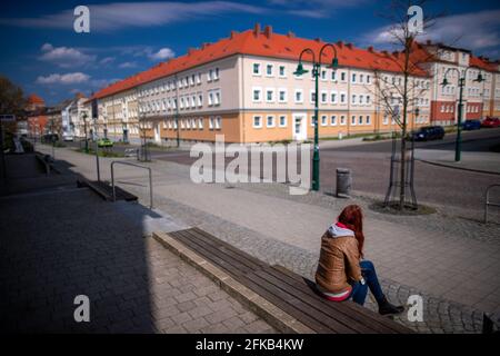 PRODUKTION - 28. April 2021, Mecklenburg-Vorpommern, Pasewalk: Eine junge Frau sitzt auf einer Bank in der Marktstraße. An der Ostgrenze zwischen Mecklenburg-Vorpommern und Brandenburg steht der wirtschaftliche Aufschwung noch lange bevor. Die Arbeitslosenquote im Landkreis Vorpommern-Greifswald liegt bei fast zehn Prozent. Foto: Jens Büttner/dpa-Zentralbild/dpa Stockfoto