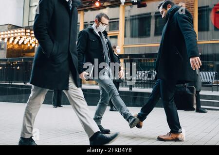 Geschäftsleute begrüßen mit Fußberühre auf dem Fußweg in der Stadt während Pandemie Stockfoto