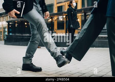Der untere Teil der Geschäftsleute begrüßt sie mit Fußberühre auf dem Fußweg In der Stadt während der COVID-19 Stockfoto