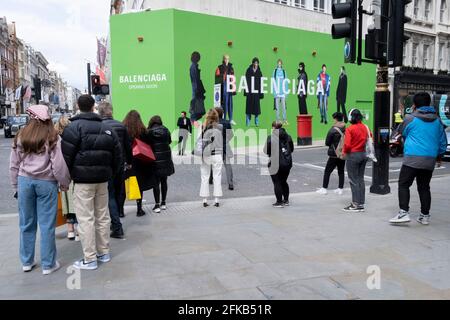 Die Käufer überqueren die Straße in Richtung des temporären Hortens für Balenciaga, ein Einzelhandelsgeschäft, das am 27. April 2021 in der Bond Street in London, England, eröffnet wird. Balenciaga ist ein Modehaus, das 1917 vom spanischen Designer Cristóbal Balenciaga in San Sebastián, Spanien, gegründet wurde. Stockfoto