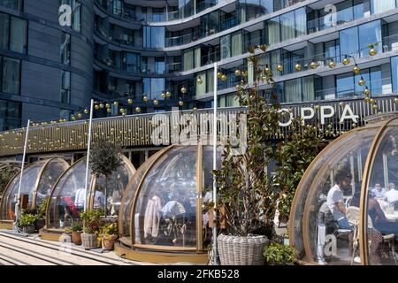 Da die Sperrbeschränkungen von Covid weiterhin lockern und unwesentliche Geschäfte wieder eröffnet werden, genießen die Gäste am 26. April 2021 in London, England, das Restaurant „Coppa Club“, das sich unterhalb von Luxusapartments in der Nähe des Tower of London befindet, im Freien. „Coppa Club“ gehört zur Restaurantkette der Strada, die sich auf italienische Küche spezialisiert hat. Stockfoto