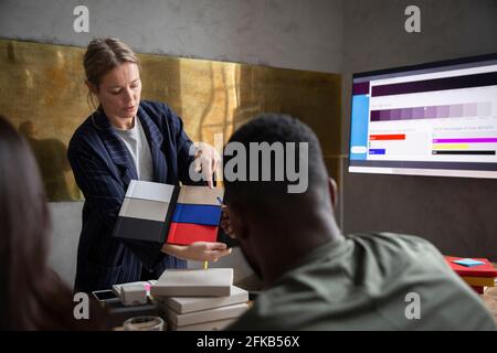 Weibliche Profikollegen, die mit Kollegen Farben auswählen, während sie im Büro diskutieren Stockfoto