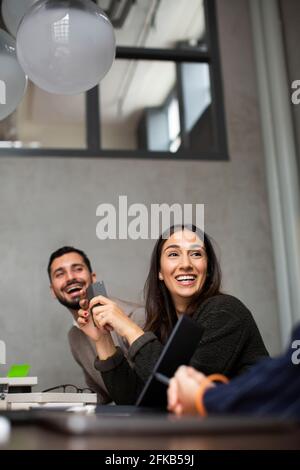 Lächelnde Geschäftsfrau im Gespräch mit Kollegen während des Meetings im Büro Stockfoto