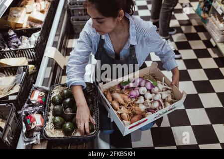 Aus der Perspektive der Verkaufsfrau, die Obst und Gemüse arrangiert Im Delikatessengeschäft Stockfoto