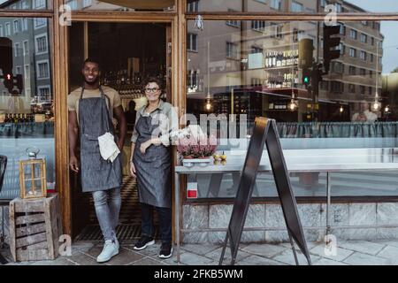 Porträt von lächelnden männlichen und weiblichen Kollegen an der Tür von Feinkostladen Stockfoto