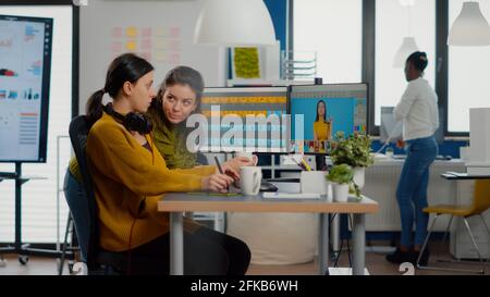 Selbstbewusste Frauen Foto-Editoren sitzen am Arbeitsplatz in kreativen Studio Retusche Foto, Art Director erklärt Farbe greding Technik. Retuschers Bearbeitung mit Zeichentablett und Stylus Bleistift Stockfoto