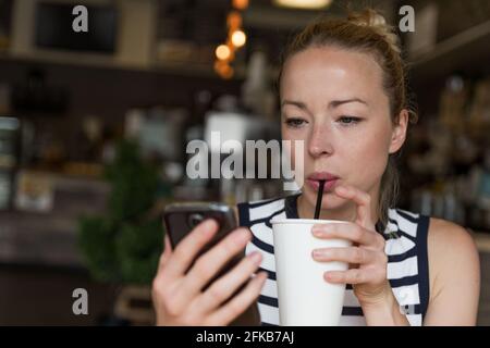 Nachdenkliche Frau news Lesen am Handy während Kaffee trinken im Coffee Shop. Stockfoto