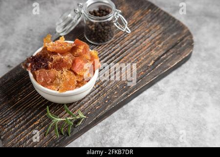 Stücke getrocknetes Fleisch mit Gewürzen auf einem Holzschneidebrett. Stockfoto