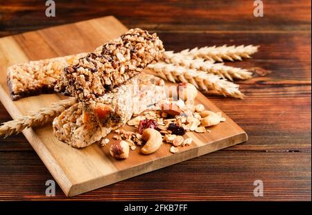 Bund gemischter glutenfreier Müsliriegel mit getrockneten Früchten & verschiedenen Nüssen, Holzhintergrund. Gesundes veganes Superfood, verschiedene Fitnessdiät sn Stockfoto